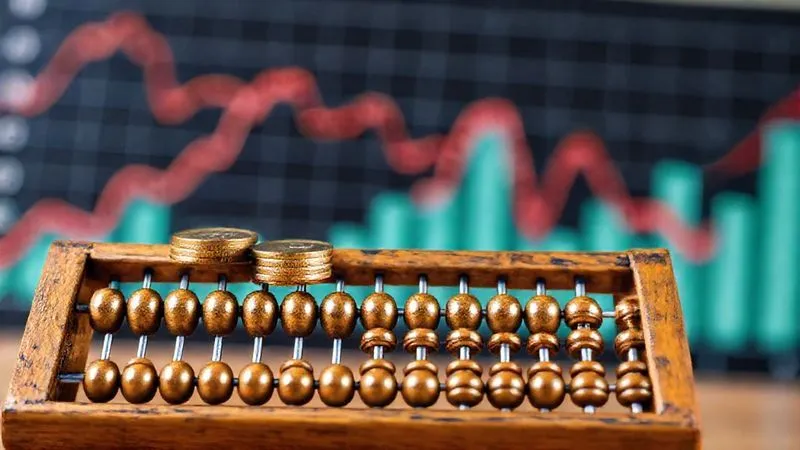 A photorealistic image of a vintage abacus with a few coins strategically placed on its beads, symbolizing the careful and calculated accumulation of wealth over time. In the background, a blurred, dynamic graph represents fluctuating income, all under cinematic lighting and sharp focus. professional photography, 8K, depth of field, shot on a high-end DSLR.