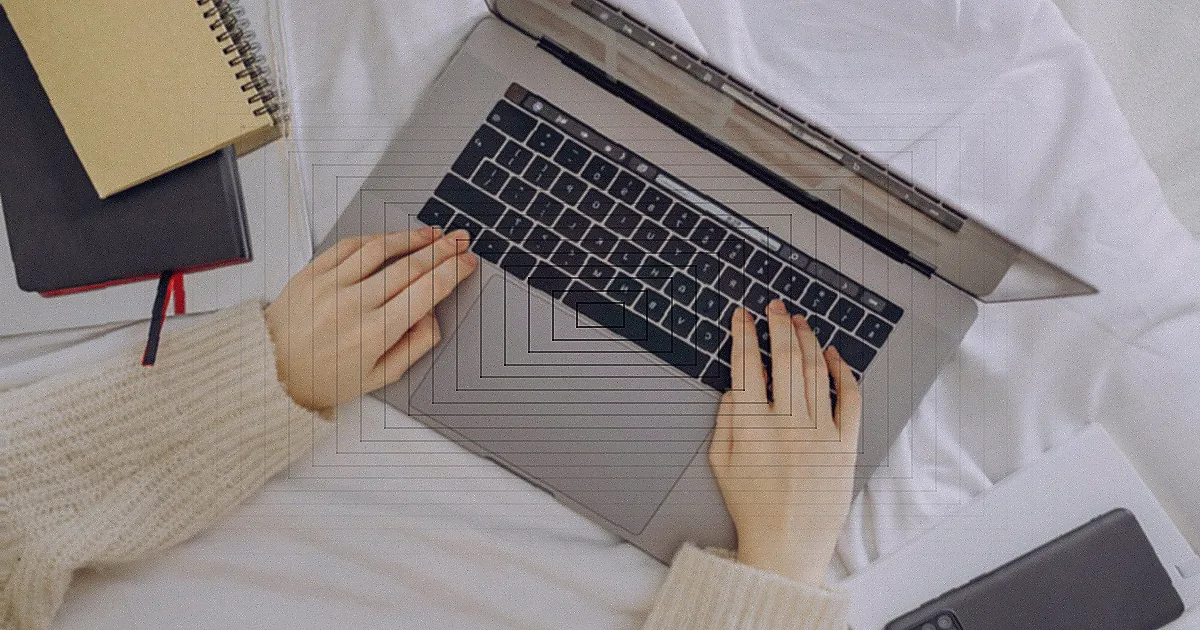 A tired woman in a red sweater leans her head on a desk with a laptop, symbolizing workplace fatigue. — Foto: Andrea Piacquadio / Pexels