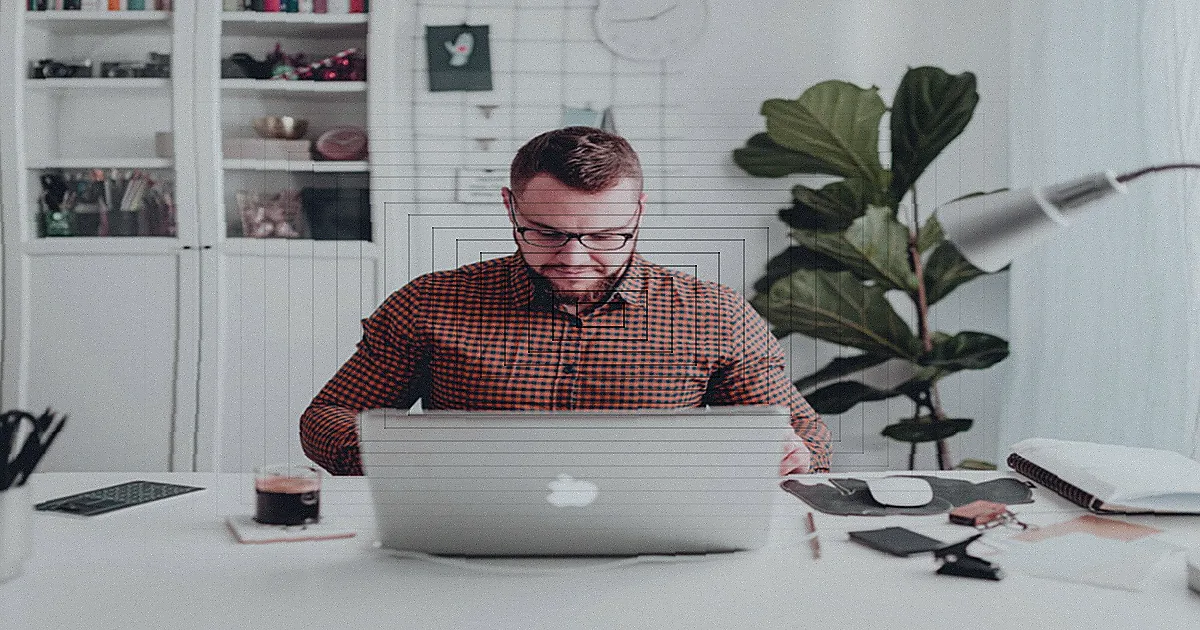 A man enthusiastically raises his arms while working remotely from home on a laptop with headphones. — Foto: Gustavo Fring / Pexels